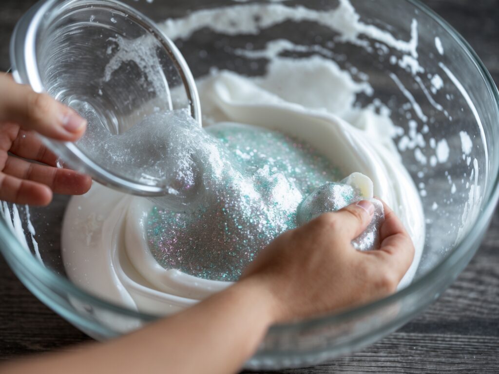 Adding glitter to the clear slime mixture for a sparkling effect